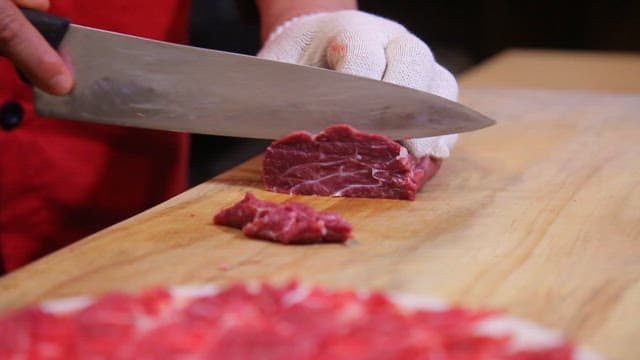 Slicing raw meat on a wooden cutting board