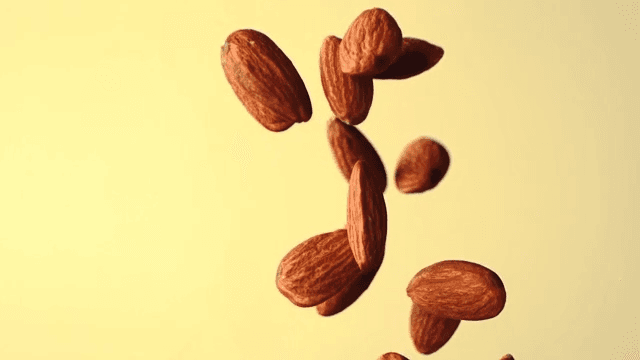 Almonds falling in slow motion against a yellow background