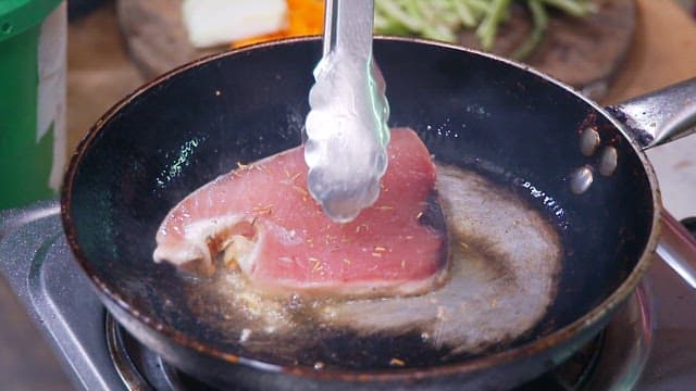 Tuna steaks cooked in hot oil in a frying pan