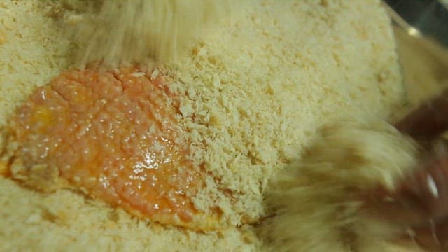 Coating the pork with egg and breadcrumbs
