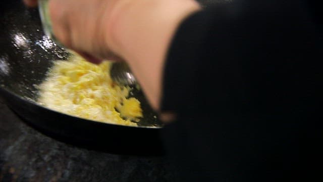 Cooking scrambled eggs with green onions in a wok