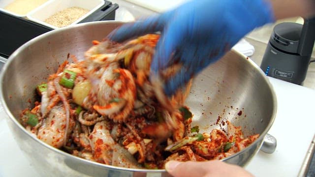 Mixing spicy seasoning and webfoot octopus in a large bowl