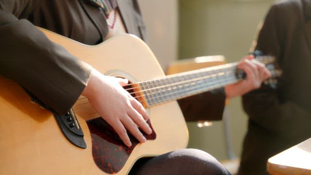 Student playing an acoustic guitar