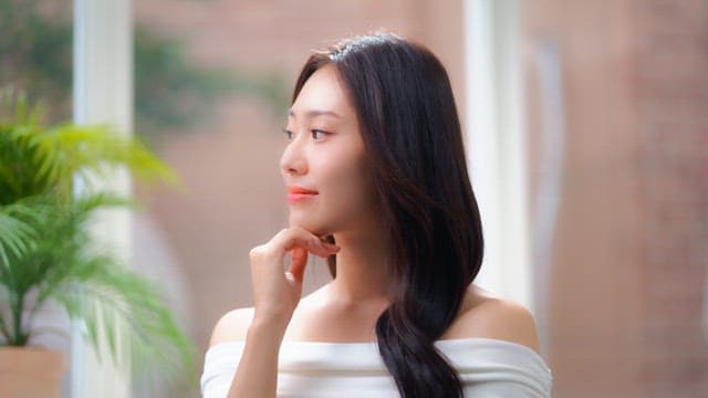 Woman's face smiling brightly in a room with sunlight through the window