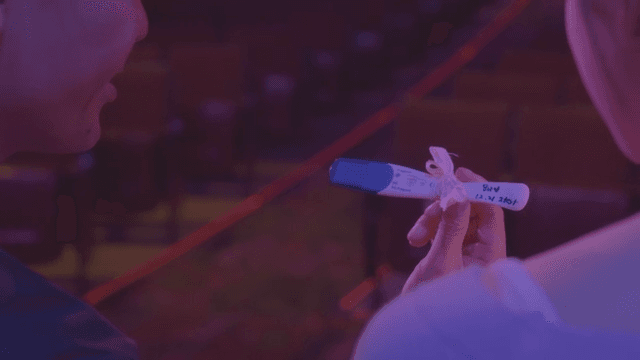 Lovers examining a pregnancy test in a dimly lit room