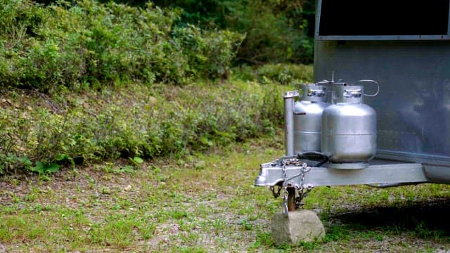 Propane tanks beside a trailer in a forest