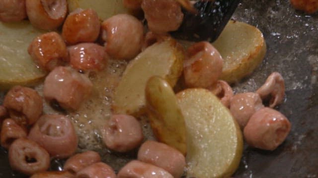 Grilled pork intestines and potatos sizzling in oil on a hot pan