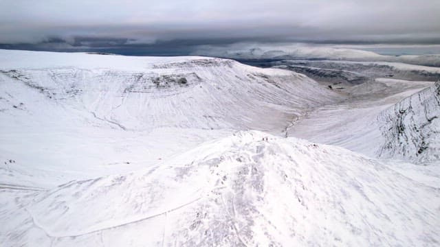 Snow-covered mountain range under cloudy sky
