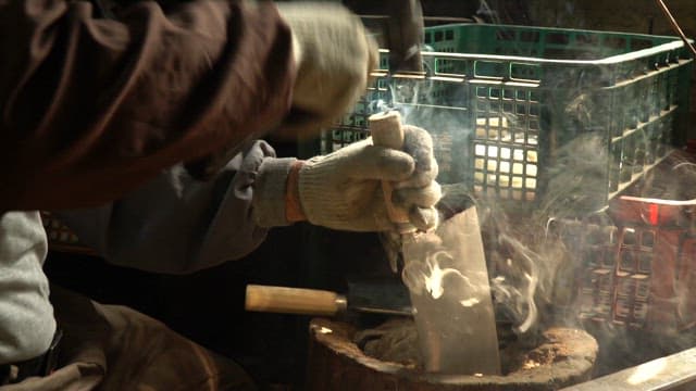 Craftsman forging a metal blade with smoke