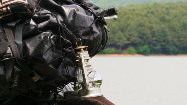 Camping lantern on the backpack by a quiet lakeside