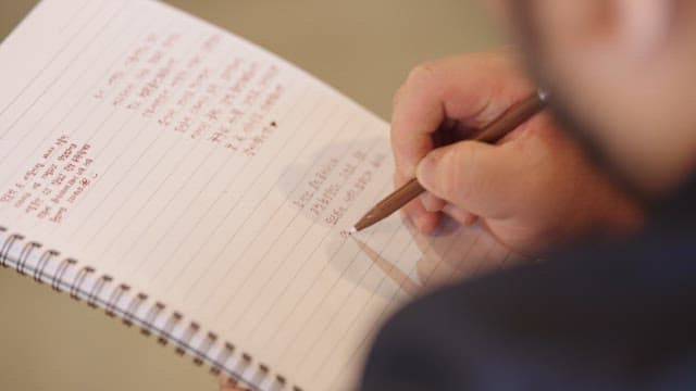 Person writing notes with a brown pen