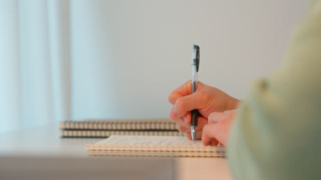 Man writing at a desk in a calmly lit room
