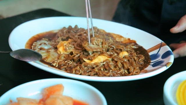 Stirring cheese blackbean ramyeon with chopsticks