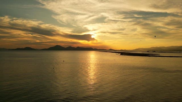 Sunset over a calm sea with distant mountains