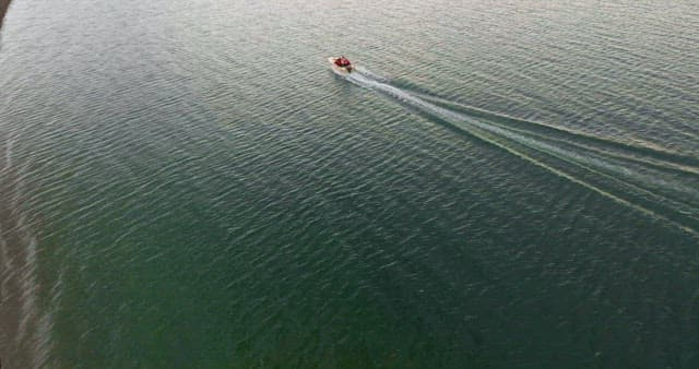 Boat cruising on a lake near a campsite