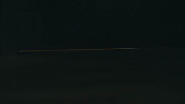 Person's feet peeking through a slightly open door late at night