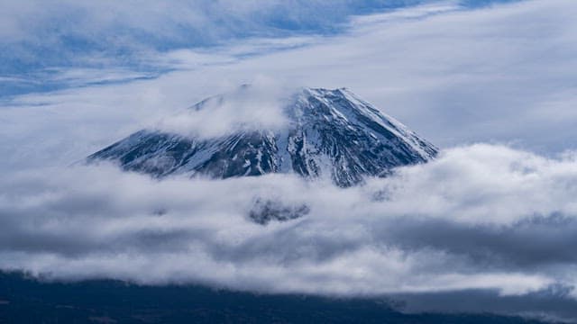 Snow-capped Mount Fuji surrounded by clouds