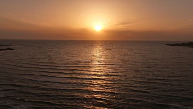 Sunset over a calm ocean with gentle waves
