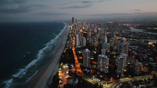 Coastal city with buildings lit up at sunset
