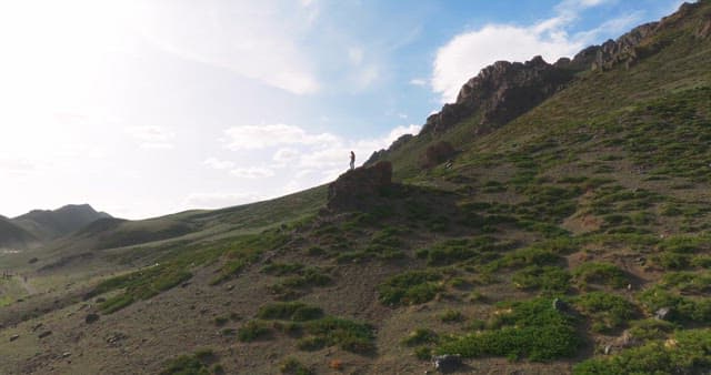 Person standing on a rock on the side of a mountain