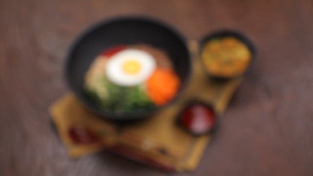 Soybean paste soup and bibimbap with vegetables and egg on a table