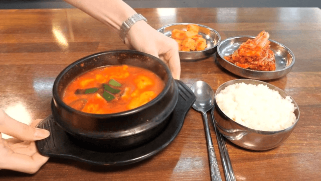 Soft tofu stew served on a table with rice and side dishes