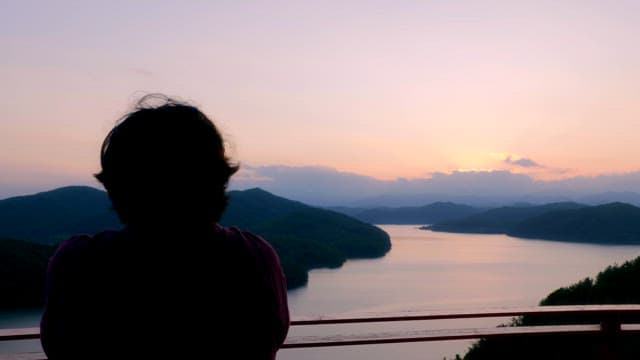 Person enjoying a serene lake view at sunset