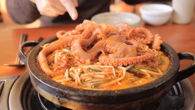 Spicy seasoned braised octopus cooking on a hot plate