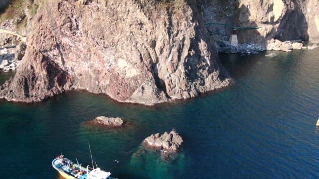 Aerial View of a Fishing Boat by Rocky Cliffs