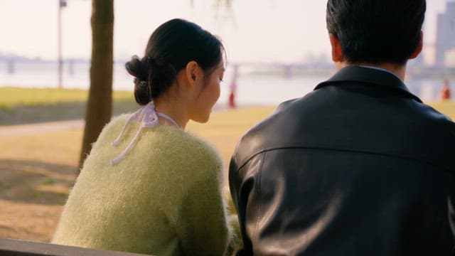 Couple sitting on a park bench by the river