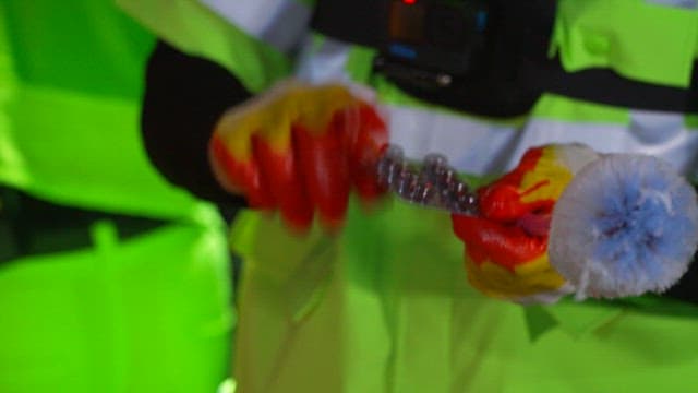 Street cleaner in a reflective vest examining garbage