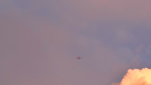Airplane flying through colorful clouds