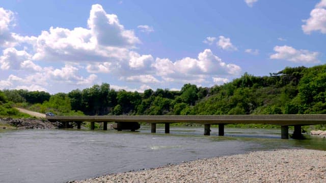 Serene river with a bridge and lush greenery