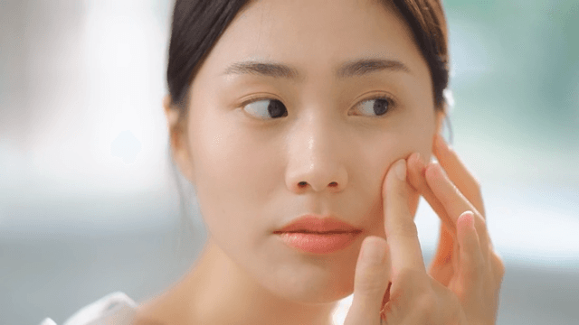 Woman putting an acne patch on her blemished face