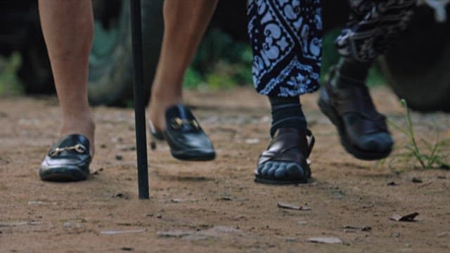 Person Supporting a Person Using a Cane on a Dirt Road