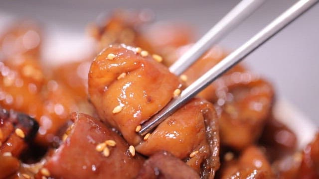 Chopsticks holding glazed seasoned pork intestines
