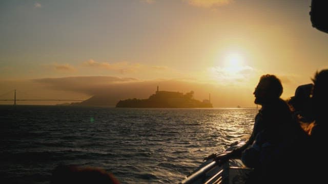 Sunset over the sea with silhouetted travelers
