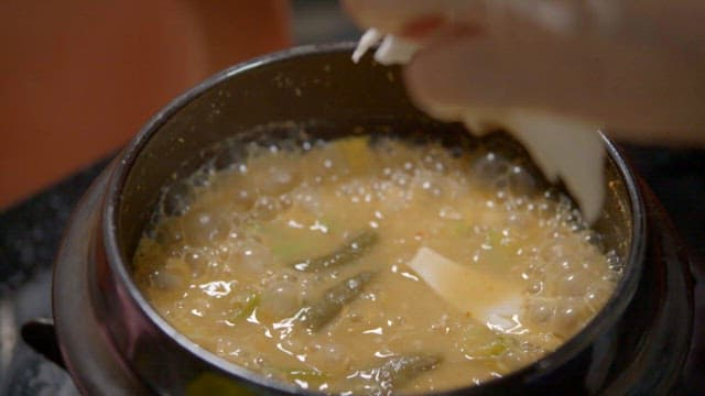 Fresh mushrooms in soybean paste stew boiling in a earthen pot