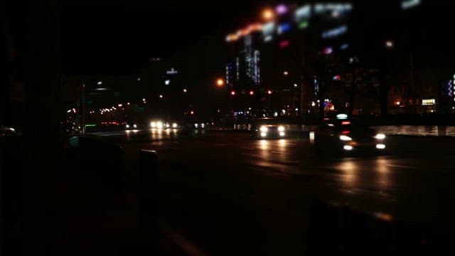 Nighttime city street with moving cars and pedestrians