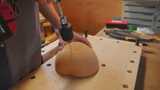 Person drilling a gourd on a workbench