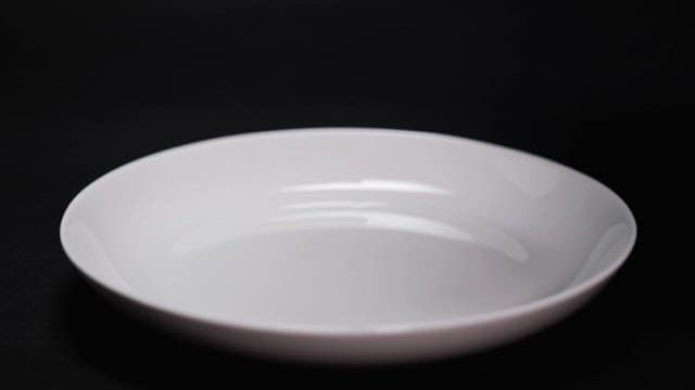 Dark chocolate syrup being poured into a white bowl