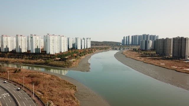 Serene urban riverside with tall apartment complex on a clear day