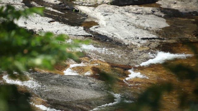 Cool water flowing through rocky valley on a sunny day