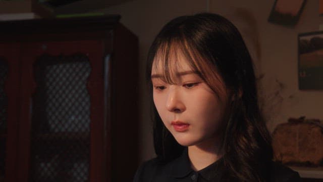 Woman sitting indoors with a thoughtful expression