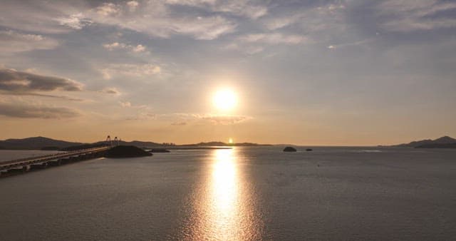 Sunset over a calm sea with a bridge