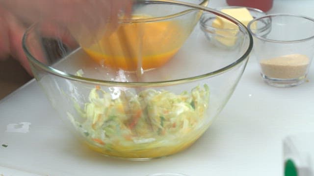 Mixing egg and chopped vegetables in a glass bowl with chopsticks