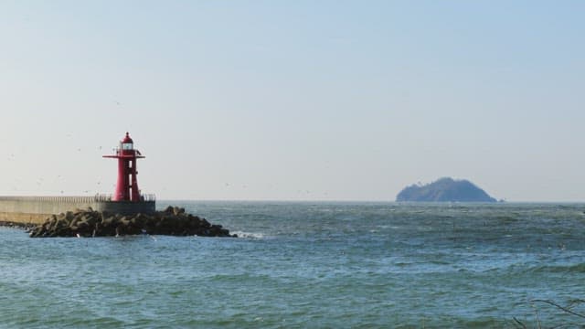 Red lighthouse by the sea on a sunny day