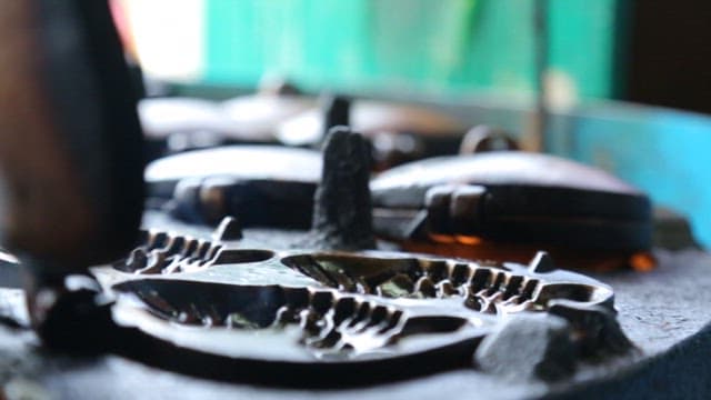 Batter being poured into a hot mold of fish-shaped pastry