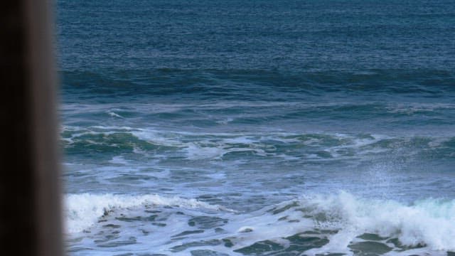 Blue and white waves crashing onto a peaceful beach in the midday