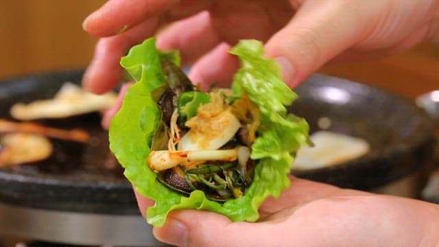 Preparing a Korean lettuce wrap with vegetables